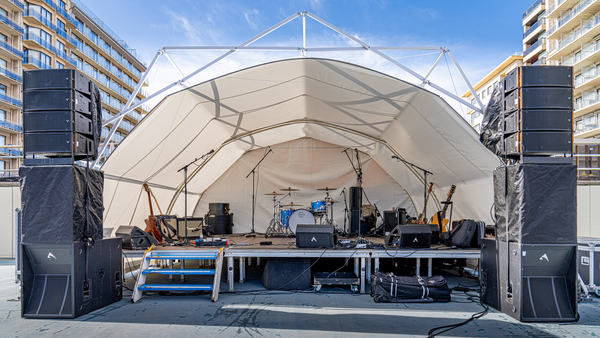 Konligo Fastival event structure with full white inner backdrop and membrane used as a covered outdoor stage setup with musical instruments and speakers, now available on MTN SHOP US.