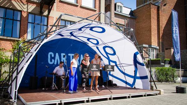 Konligo Fastival event structure with custom printed membrane and outsidde printed backdrop hosting an outdoor live performance in front of a brick building, now available on MTN SHOP US.