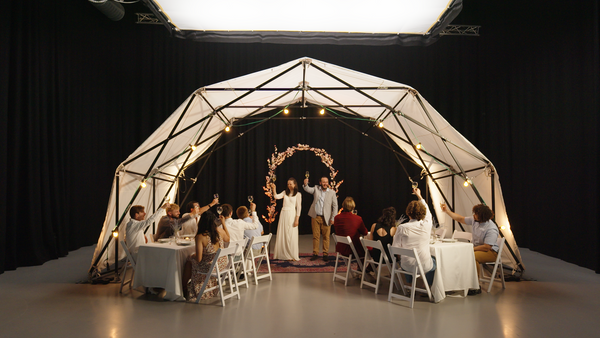 Konligo Fastival event structure with white membrane used as a wedding canopy, featuring guests toasting newlyweds at a dinner reception, now available on MTN Shop US.