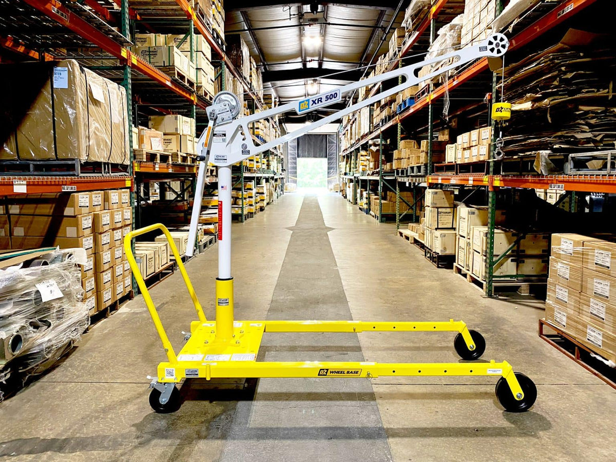 An OZ Lifting Products XR 500 Davit Crane with a white mast and boom, mounted on a yellow portable mobile wheel base inside a warehouse aisle. - imagen 4
